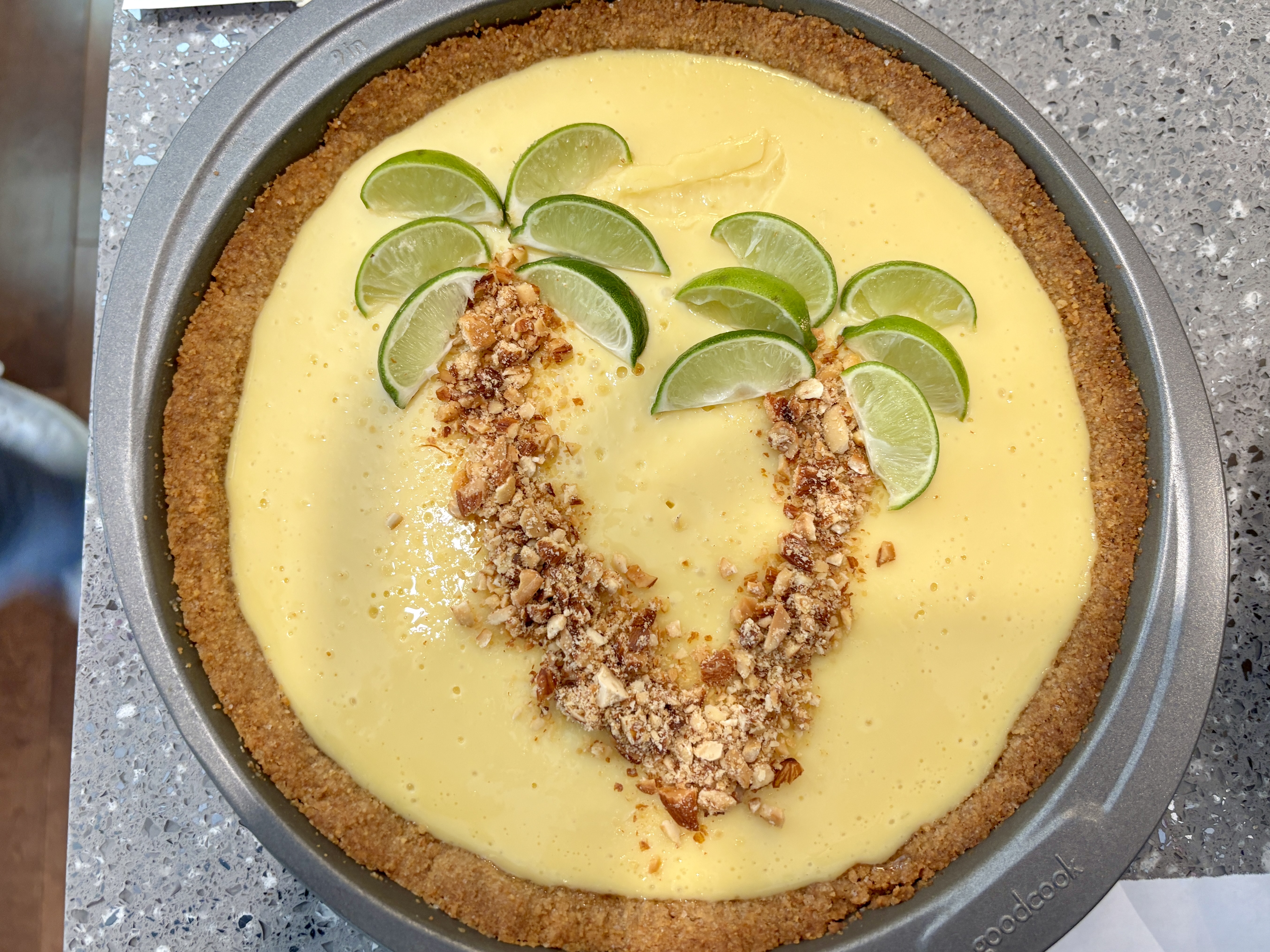 Key lime pie decorated with lime-slice palm trees and crushed nuts.
